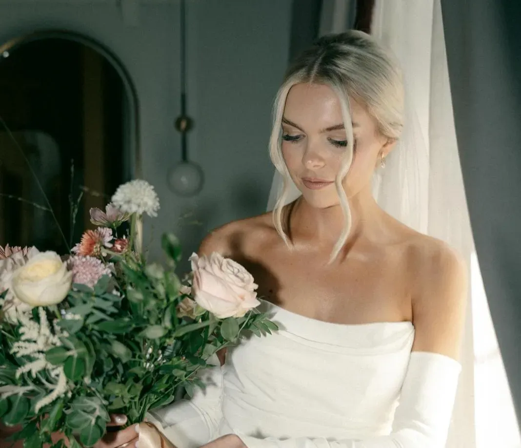 A bride by a window holding her bouquet